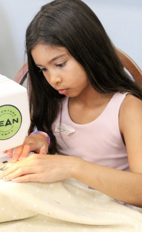 Camper sewing at a DEAN sewing machine in Machine Sewing camp