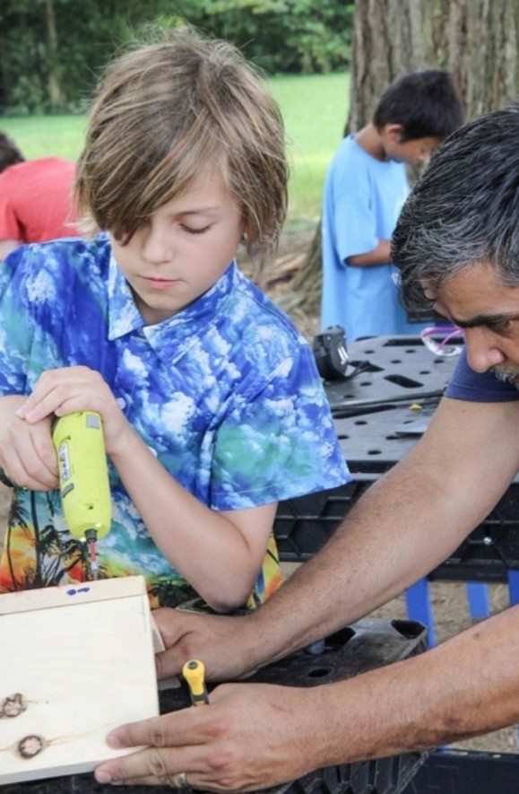 Counselor helping a camper drill wood in Woodworking camp