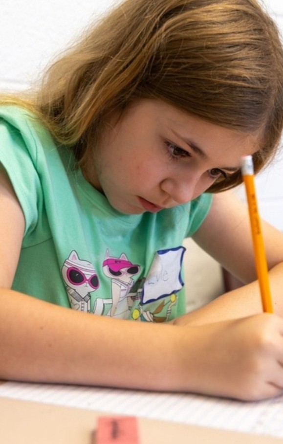 Camper concentrating while writing with a pencil in Writing & Illustration camp
